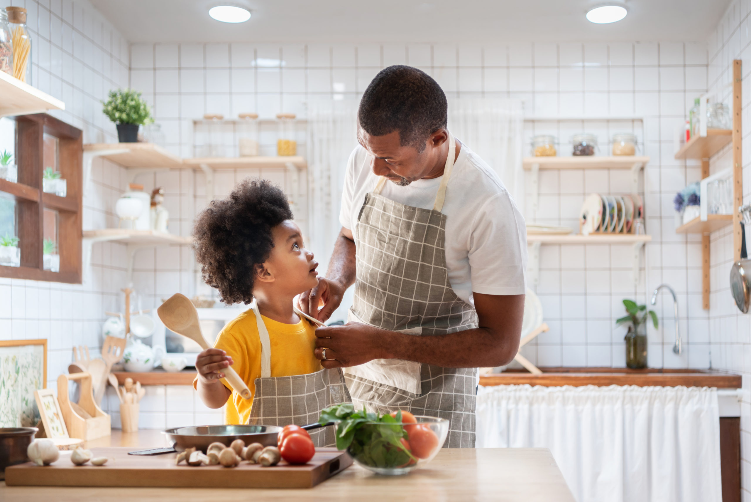 Happy African Father And Son Dress Up Together Before Cooking In